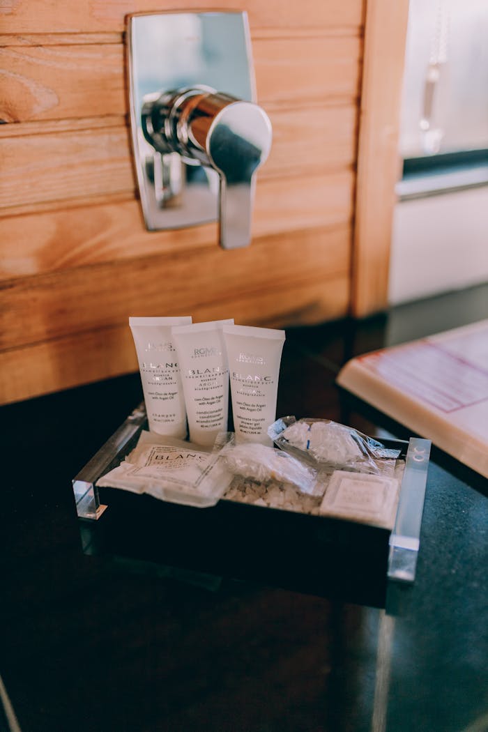 Mastering the First Impression: Your intriguing post title goes here Elegant hotel bathroom amenities placed on a wooden counter beside a chrome faucet.